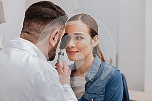 Pleasant nice doctor using ophthalmoscope