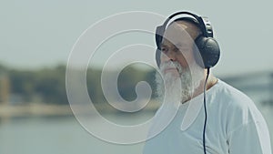 Pleasant old man has a relax listening music with headphones