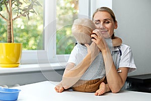 pleasant pediatrician hugs child patient in clinic office. empathy and love your job concept