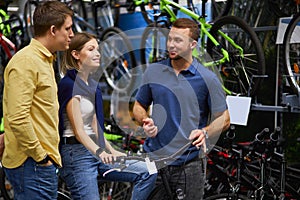 Pleasant salesman try to sell sportive bicycle for customers