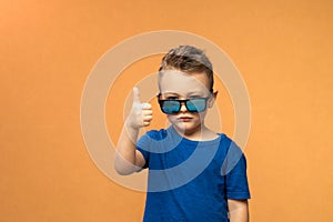 Pleasant satisfied boy shows thumbs up looking at camera, portrait. Attractive smiling boy in blue casual t-shirt posing