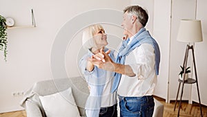 Pleasant senior couple dancing and smiling to each other