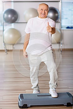 Pleasant senior man practicing step aerobics