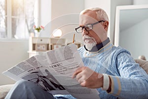 Pleasant senior man reading article in the newspaper