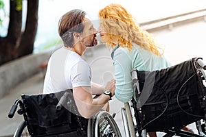 Pleasant senior wheelchaired couple sitting nose to nose