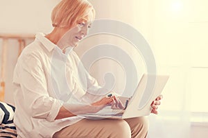 Pleasant senior woman using her laptop at home