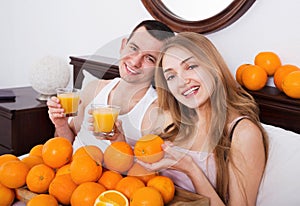 Pleasant smiling couple with ripe oranges and freshly juice