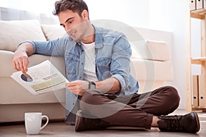 Pleasant smiling man sitting on the floor