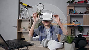 Pleasant smiling teen boy looking at camera and wearing virtual reality headset to play video games