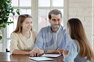 Pleasant smiling young married couple meeting with female bank consultant