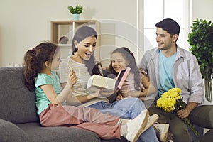 Pleasant surprised mom with happy expression opening gift box from kids