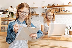 Pleasant teenage barista checking her to-do list
