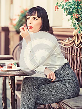 Pleasant time and relaxation. Delicious gourmet cake. Woman attractive brunette eat gourmet cake cafe terrace background