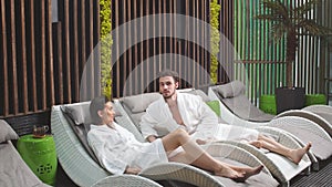 Pleasant unshaven man looking at relaxing girlfriend in the spa center.