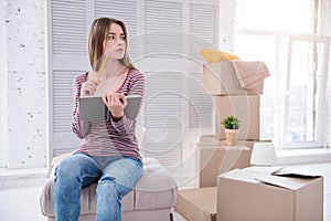 Pleasant woman checking the list of items before moving out