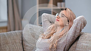 Pleasant woman relaxing falling on comfortable couch enjoying lazy weekend at home stress free alone
