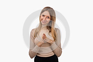 Pleasant young blond woman hold hands on heart thanking for compliments or praises. Studio shot, white background