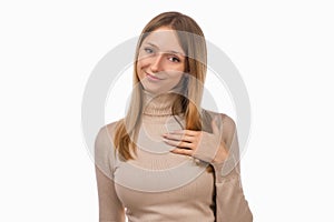 Pleasant young blond woman hold hands on heart thanking for compliments or praises. Studio shot, white background