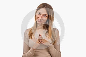 Pleasant young blond woman hold hands on heart thanking for compliments or praises. Studio shot, white background