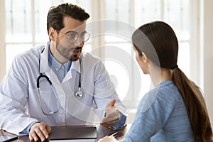 Pleasant young handsome male doctor talking to patient.