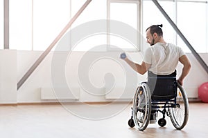 Pleasant young invalid exercising with weights in the gym