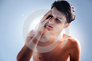 Pleasant young man touching his face