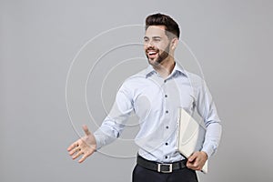 Pleasant young unshaven business man in light shirt posing isolated on grey background. Achievement career wealth