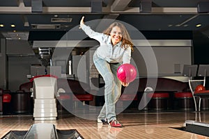 Pleasant young woman throws a bowling ball