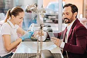 Pleasant young woman treating male hands