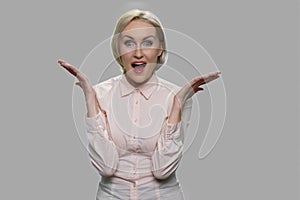 Pleasantly shocked business lady on gray background.