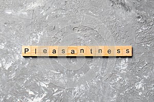 Pleasantness word written on wood block. pleasantness text on cement table for your desing, concept