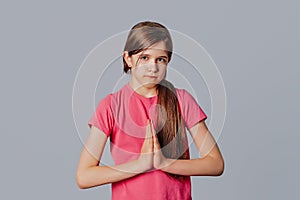 Please darling help me out. Portrait of cute young girl pulling lips down in upset smile, frowning and holding palms in pray while