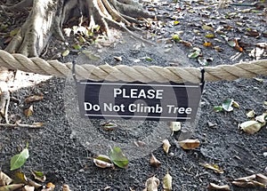 please do not climb tree sign on rope with tree in background