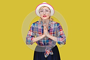 Please forgive me. or give me one more chance, Portrait of hopeful mature woman in casual style with hat and eyeglasses standing