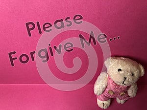 Please forgive me the written note on the pink background with cute sad teddy bear