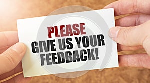 PLEASE GIVE US YOUR FEEDBACK word inscription on white card paper sheet in hands of a businessman