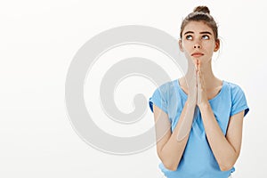 Please god help me and hear my prayers. Portrait of gloomy intense and worried cute woman in blue t-shirt with bun