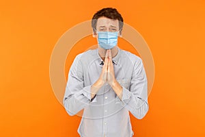 Please help me. Portrait of sad worry young worker man with medical mask standing with palm hands, worry and looking at camera