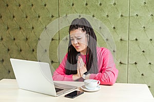 Please help me! Portrait of young beautiful student with black dreadlocks hairstyle in pink blouse sitting in cafe and talking