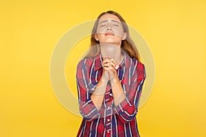 Please I`m begging! Portrait of despaired ginger girl in shirt keeping arms in prayer gesture and holding up head, appealing to