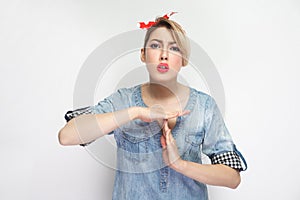 Please I need more time. Portrait of beautiful young woman in casual blue denim shirt with makeup and red headband standing with
