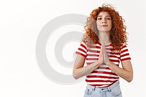 Please I need you. Attractive tender feminine curly redhead woman asking favour press palms pray gesture plead smiling photo
