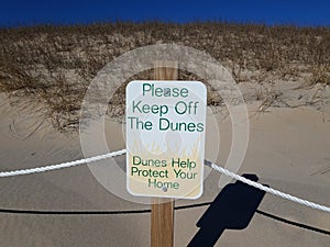 please keep off the dunes sign with sand and plants