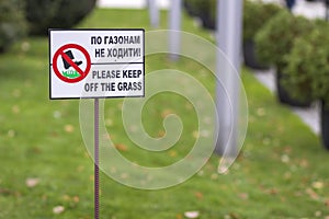 Please keep off the grass sign on green lawn grass blurred bokeh background on sunny summer day. City lifestyle and nature