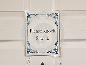 Please knock and wait sign on white door