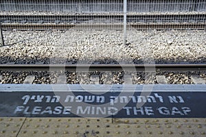 `Please mind the gap` warning sign at train station platform edge.