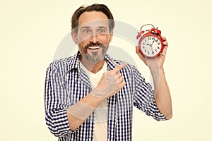 Please observe time. Mature man pointing finger at alarm clock. Mature timekeeper with analog clock. Bearded senior man photo