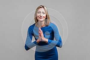 Please! Portrait of upset woman holding hands in prayer and pleading. isolated on gray background