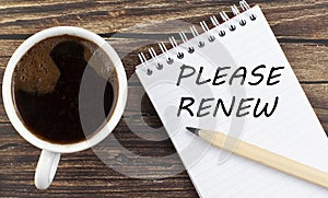 PLEASE RENEW text on notebook with coffee on wooden background