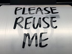 Please reuse me sign on roll of plastic bags in supermarket